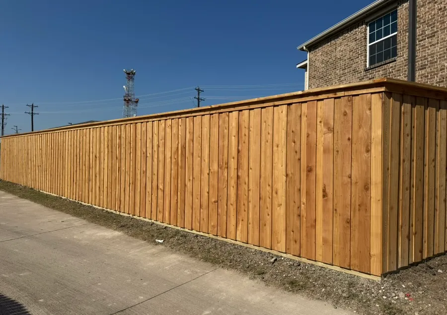 Long new cedar board-on-board privacy fence beside a brick home