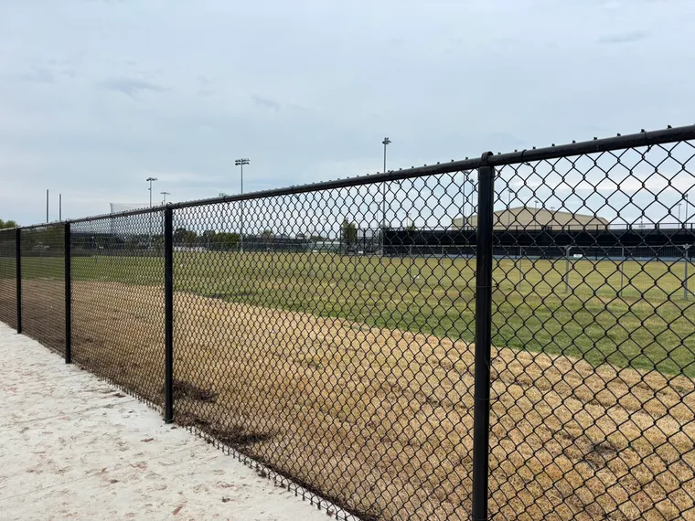 Black vinyl-coated chain-link fence installed around an athletic field