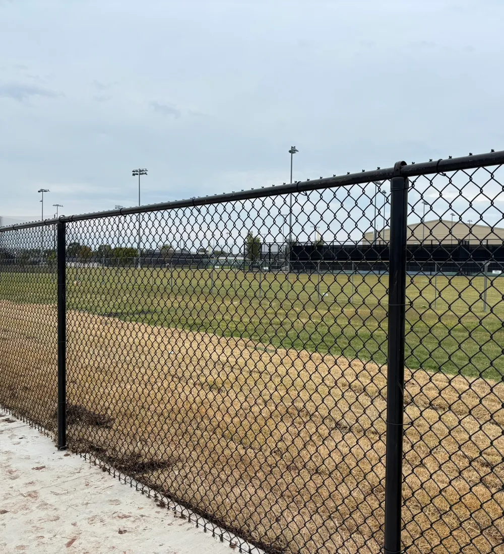 Black vinyl-coated chain-link fence installed around an athletic field