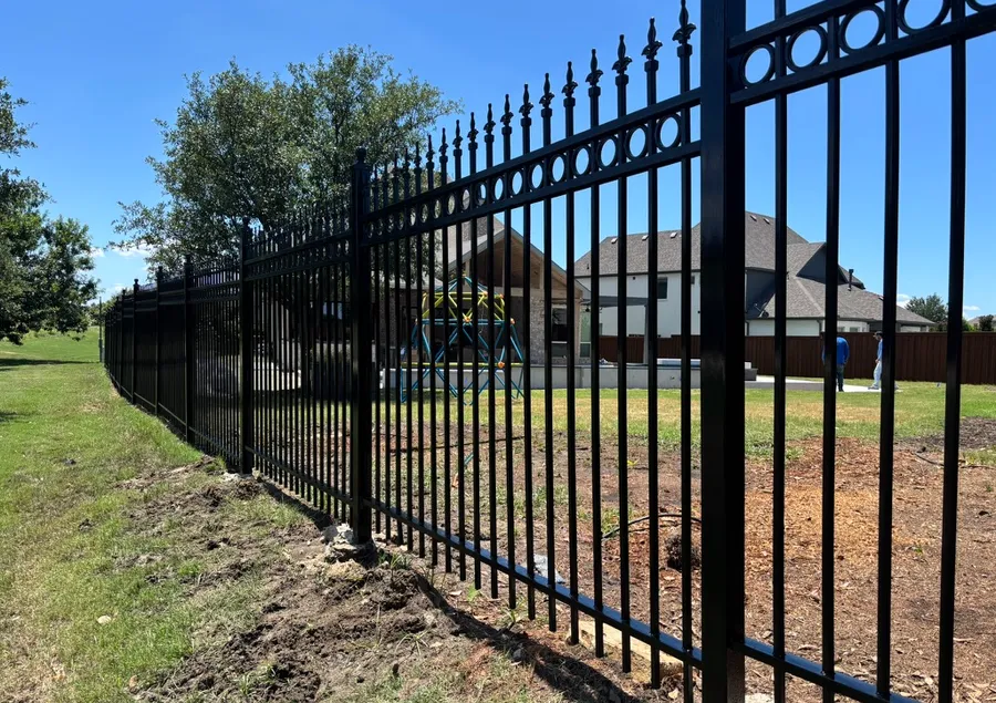 Black ornamental steel fence with spear-top pickets around a property