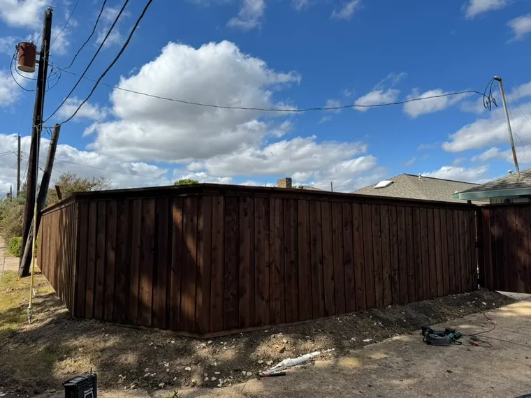 Completed dark-stained wood fence replacement along a residential alley